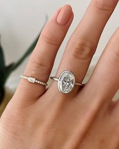 a woman's hand wearing a ring with a diamond on the middle and side