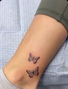 two butterflies tattoo on the side of a woman's left leg, with one butterfly flying