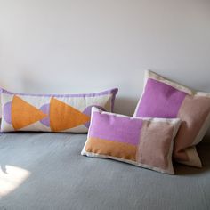 two pillows sitting on top of a bed in front of a white wall and window