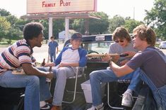 four people sitting in the back of a pick - up truck talking to each other