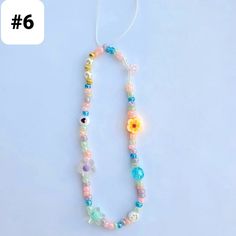 a necklace made with beads and flowers on a white background, the number six is in front of it