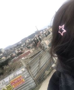 a girl with pink hair clips on her head looking out over a cityscape