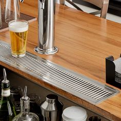 a wooden counter top topped with lots of bottles and glasses next to a faucet