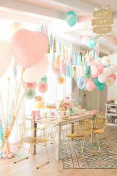 a room filled with balloons and tables covered in pink, blue, yellow and green decorations