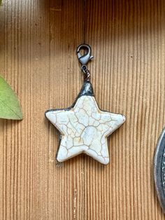 a white star shaped keychain hanging from a metal hook on a wooden table