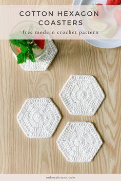 three crocheted coasters sitting on top of a wooden table with strawberries