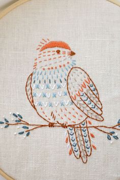 an embroidered bird sitting on top of a tree branch