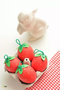 some strawberries are in a carton on a table next to a figurine