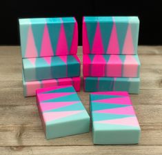 four pieces of pink and blue soap sitting on top of a wooden table next to each other