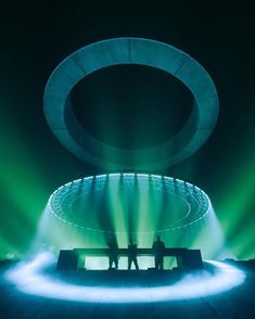 two people sitting on a bench in front of a green and white light display with circular lights