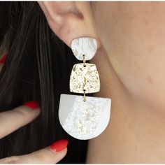 a close up of a person wearing some kind of earring on her ear and holding onto another piece of jewelry