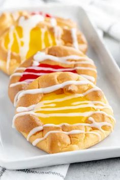 some very tasty looking pastries on a white plate with red and yellow icing