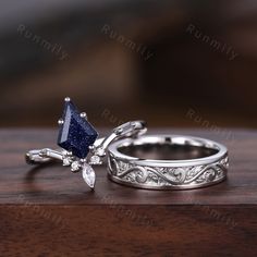 two wedding rings with blue and white diamonds on them sitting on top of a wooden table