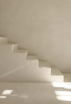 a cat sitting on top of a set of white stairs next to a window in a room