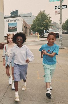 three young children are walking down the sidewalk