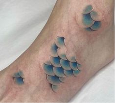 a person has a tattoo on their foot that is shaped like fish and features blue water droplets