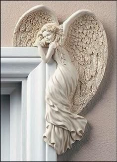 an angel statue hanging on the wall next to a window