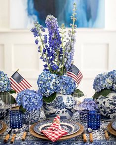 a blue and white table setting with flowers in vases