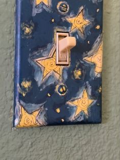 a blue and yellow light switch cover with stars on the wall next to an electrical outlet