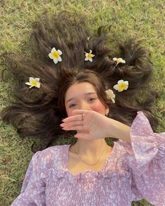 a woman laying on the grass with her hair blowing in the wind and daisies