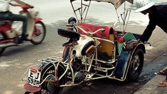 an old motorcycle with a side car attached to it on the street next to people