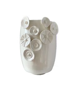 a white vase filled with lots of buttons on top of a white wall mounted object