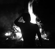 a man standing in front of a fire with his hands on his head and arms behind his head