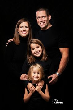 a family posing for a photo in the dark with their arms around each other and smiling at the camera