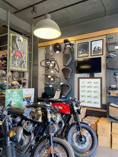 two motorcycles parked next to each other in a room with shelves and pictures on the wall