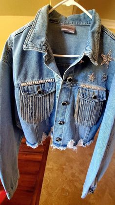 Sparkly, Country Glam, Rhinestone Crop, Distressed Jean Jacket. Perfect for Weekend Outings, Stage Coach, Coachella, Rodeo, Night Club, Parties, Night out, Daytime Excursions, Wineries, ect. Unique One of a kind, Made to Order, Custom Order Rhinestone, Bling Jacket. Super Cute and Unique! You'll get lots of Compliments! Fun to Wear! This Jacket is a large. I recently bought this denim jacket new, plain. I added all embellishments, crystal button covers, patch stars and heart, crystal crown on back, pearl and crystal trim, crystal, tassel fringe on front pockets.  Embellishments on fabric were attached using E6000, permanent bond, which is washer/dryer safe and button coverings down the front jacket and sleeve cuffs attached using Gem-Tac permanent bond. Last step is hand sewn with clear ny Denim Jacket With Tassels, Long Sleeve Denim Jacket With Rhinestone Fringe, Bedazzled Jean Jacket, Bling Denim Jacket, Rhinestone Jean Jacket, Denim Jacket Crop, Western Denim Jacket, Bling Jacket, Rhinestone Jacket