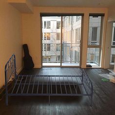 an empty room with a metal bed frame in front of a sliding glass door that leads to the balcony