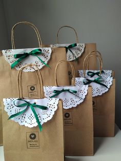 brown paper bags with white doily and green ribbon tied around the handles are sitting on a table