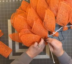 someone is working on an orange wreath made out of burlock and twine