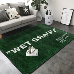 a living room with a green rug that says wet grass on the floor next to a couch