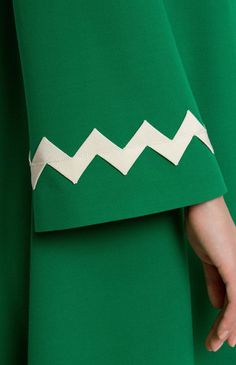 a woman's hand is shown holding onto a green dress with white chevrons