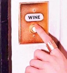 a person pointing to a wine button on a wall