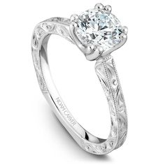 a diamond engagement ring with filigrees on the sides and an engraved band