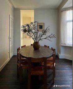 a wooden table topped with a brown vase filled with flowers on top of it next to a doorway