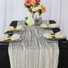 the table is set with black plates and gold place settings, along with an elegant centerpiece