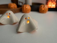 two white ghost shaped candles sitting on top of a table