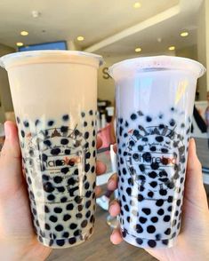 two people holding up cups with black and white designs on them