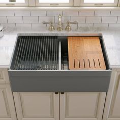 a kitchen sink with two wooden cutting boards in the bottom half and an open drawer