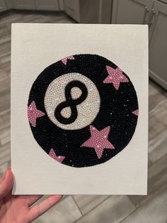 a hand holding up a black and white sticker with pink stars around the letter b