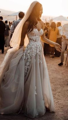 a woman in a wedding dress standing next to a group of people near a van