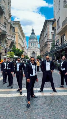 a group of men in tuxedos walking down a street