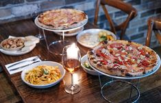 a wooden table topped with pizza and pasta