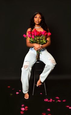 a woman is sitting on a chair with flowers in her lap and posing for the camera