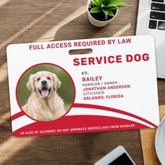 a service dog id card sitting on top of a wooden table next to a laptop