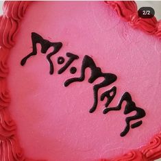 there is a pink cake with black writing on it