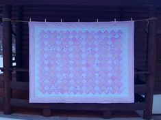 a pink and white quilt hanging from a clothesline on a clothes line in the snow